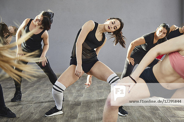 Women wearing sports clothing dancing against wall in studio