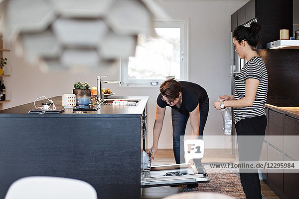 Lesbian couple working together in kitchen at home