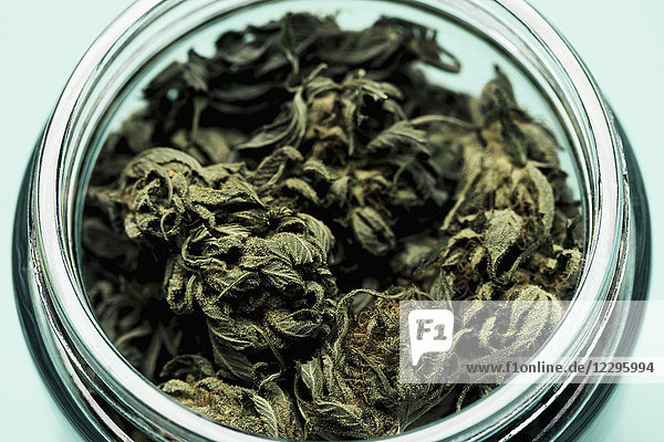 Hochwinkelansicht der Marihuana-Blätter im Glas auf dem Tisch vor schwarzem Hintergrund