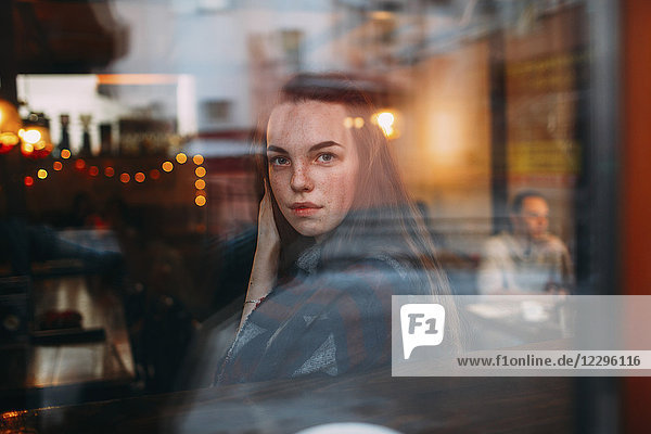 Schöne junge Frau durch das Caféfenster gesehen