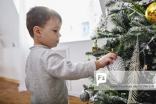 Side view of boy standing by Christmas tree at home