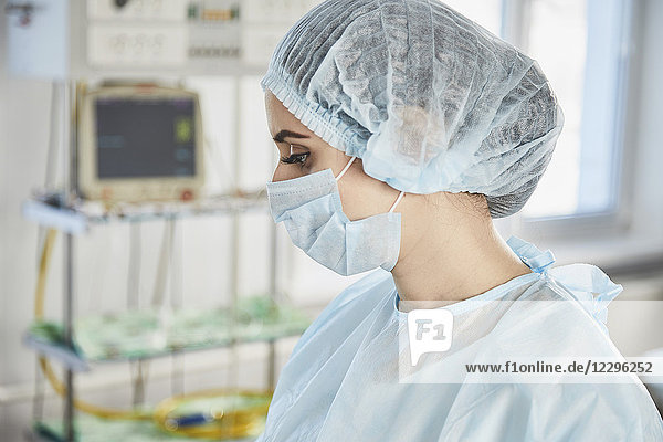 Seitenansicht des Chirurgen mit OP-Maske und Kappe im Operationssaal