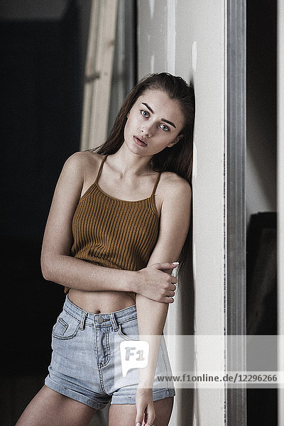 Portrait of beautiful young woman leaning on wall
