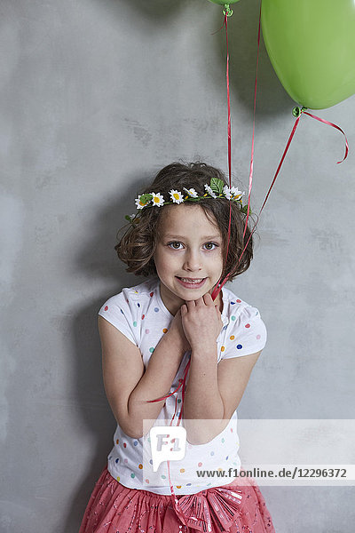 Porträt des lächelnden Mädchens mit Ballon an grauer Wand stehend