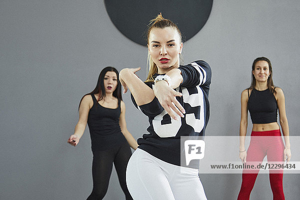 Porträt einer selbstbewussten Frau  die mit Freunden im Studio im Hintergrund tanzt.