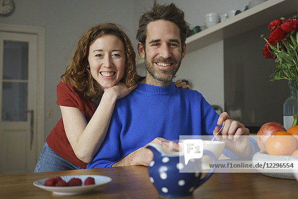 Porträt des lächelnden mittleren Erwachsenenpaares bei Tisch mit Frühstück im Zimmer