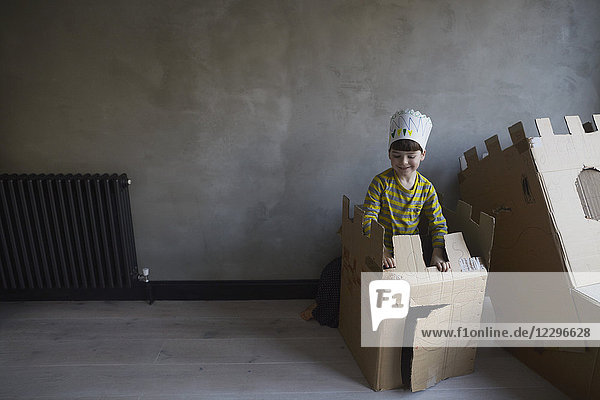 Happy boy playing with cardboard box against wall