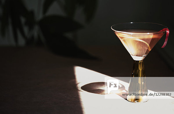 Ein Sommercocktail in einem Stielglas  das einen Schatten wirft