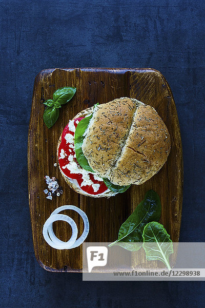 Gesundes vegetarisches Sandwich mit Fetakäse  Tomaten  Basilikum und Paprika  serviert auf einem hölzernen Schneidebrett mit Vintage-Hintergrund