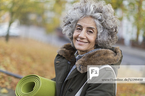 Portrait smiling,  confident active senior woman with yoga mat