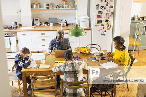 Grandparents at dining table with grandchildren doing homework