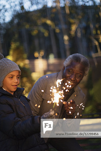 Grandfather and grandson playing with firework sparklers