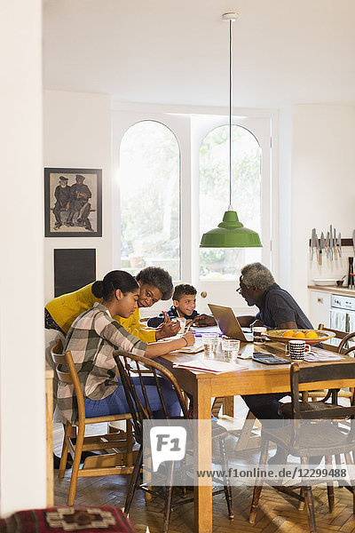 Grandparents helping grandchildren with homework at dining table