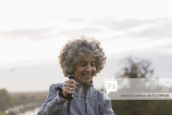 Smiling active senior woman hiking with pole