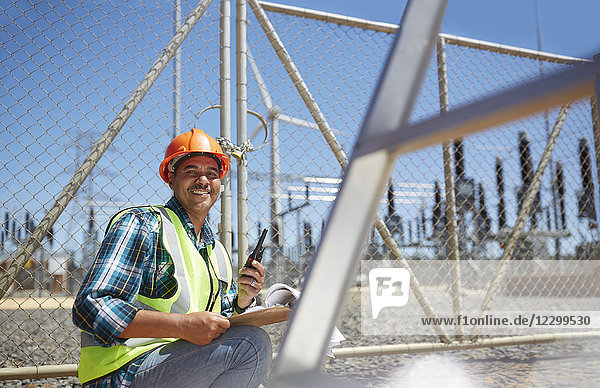 Portrait smiling  confident male engineer with walkie-talkie at power plant