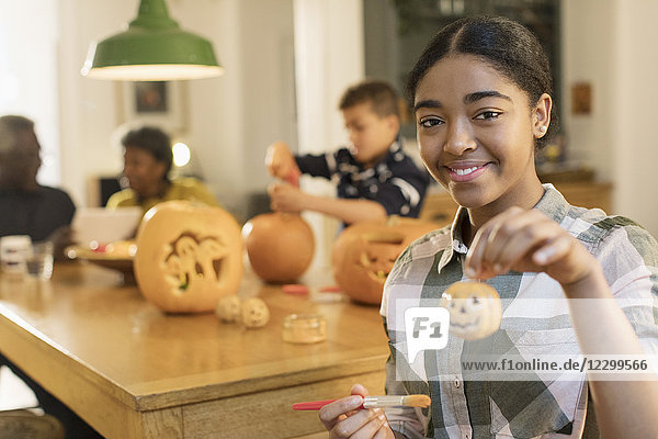 Portrait smiling  confident teenage girl holding painted Halloween pumpkin ceramic