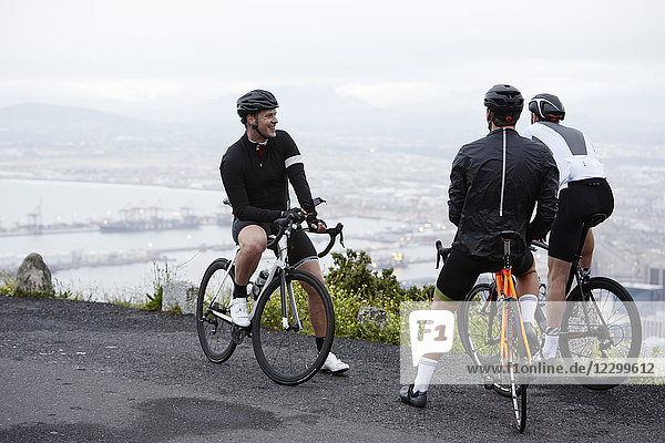 Male cyclist friends taking a break at overlook