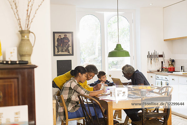 Grandparents helping grandchildren with homework at dining table