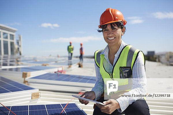 Portrait smiling  confident female engineer with digital tablet inspecting solar panels at sunny power plant