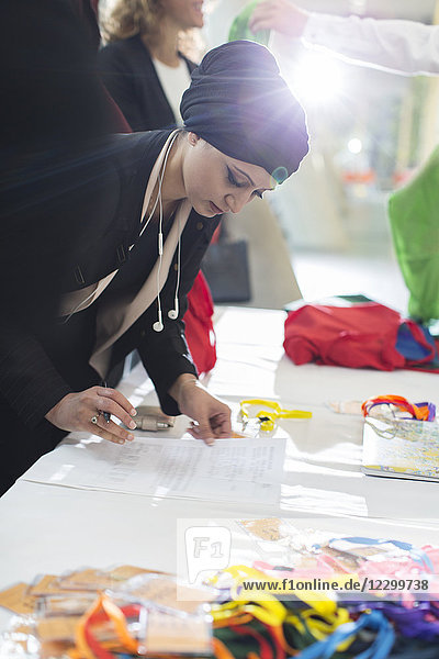 Businesswoman wearing headscarf checking in at conference registration table
