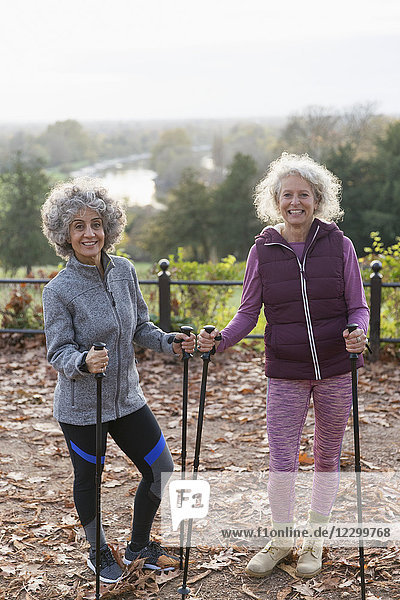 Portrait smiling  confident active senior women friends hiking with poles in autumn park