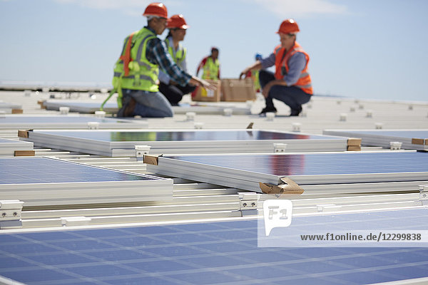 Engineers installing solar panels at sunny power plant