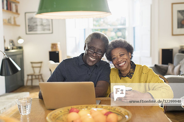 Portrait smiling  confident senior couple using laptop at dining table
