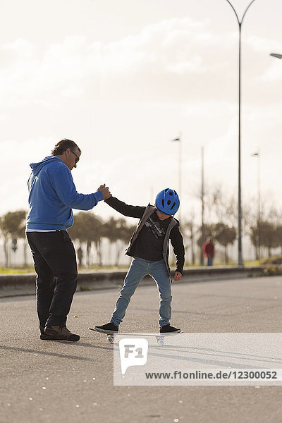 Father teaching young son to skateboard