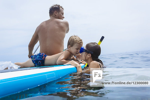 Family on sup surfboard in ocean Bali Indonesia
