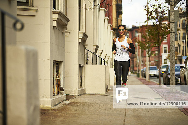 Young woman jogging on pavement along city street  Boston  Massachusetts  USA