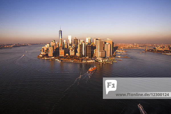Die Sonne geht an einem Herbstabend über Downtown Manhattan und dem Finanzdistrikt von New York City unter  gesehen von einem Hubschrauber aus  der über den Hafen und den East River fliegt.