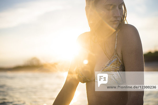 Taille nach oben Blick auf Frau im Bikini am Strand bei Sonnenuntergang