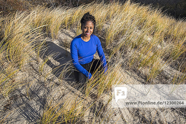 Portrait of young woman sitting alone on grass and smiling at camera  Newburyport  Massachusetts  USA