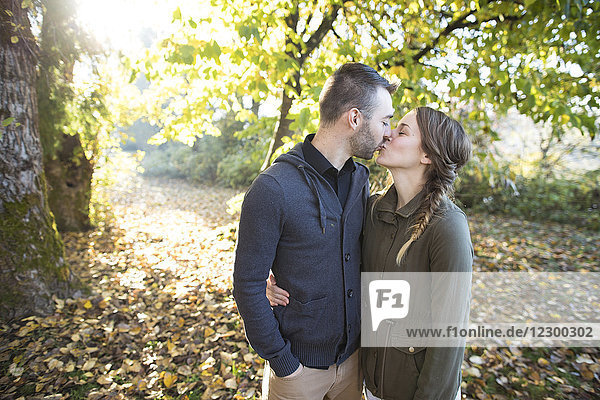 Seitenansicht  Aufnahme eines sich küssenden Paares im Park von der Taille aus