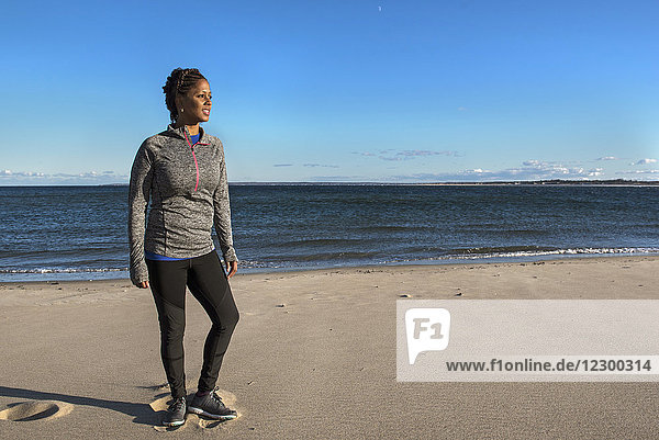 Young woman standing on sandy coastal beach on sunny day  Newburyport  Massachusetts  USA