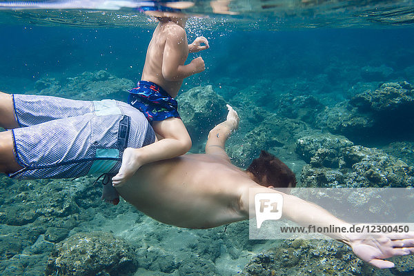 Father and son diving under water Bali Indonesia