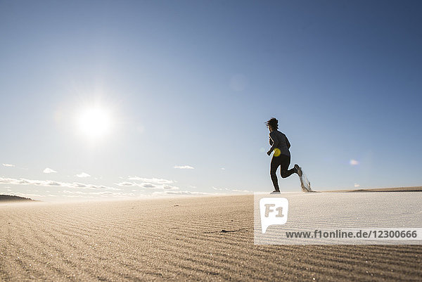 Die Sonne scheint auf eine junge Frau  die am Sandstrand joggt  Newburyport  Massachusetts  USA