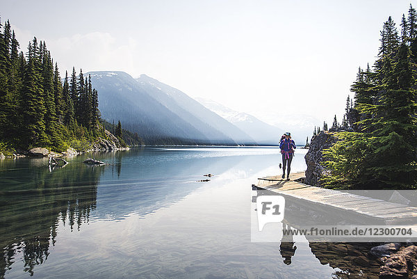 Woman backpacking on boardwalk along shore of Lake Garibaldi  British Columbia  Canada