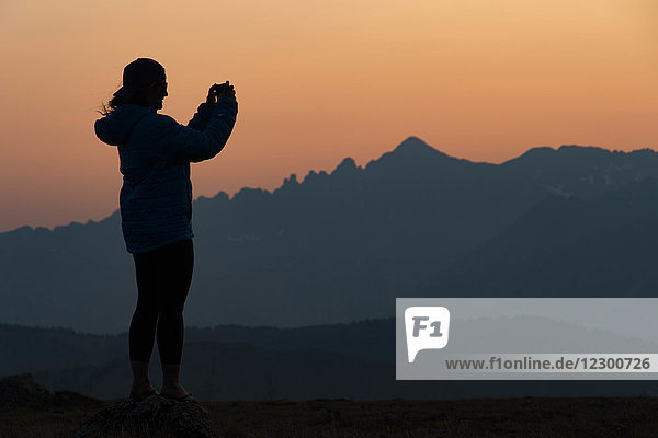 Woman taking picture with smartphone in mountains at sunset  Aspen  Colorado  USA