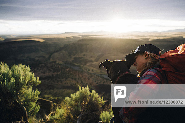 Smiling woman embracing dog in natural scenery  Trout Creek  Oregon  USA