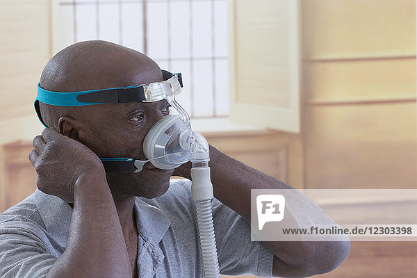 Ein Mann trägt eine CPAP-Maske (Continuous Positive Airway Pressure) zur Behandlung von Schlafapnoe.