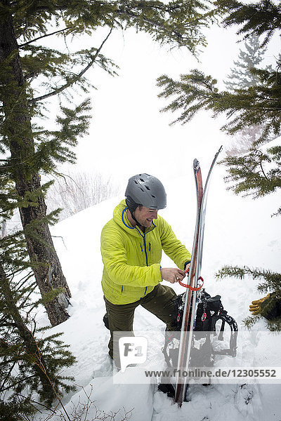 Backcountry skier strapping skis to backpack