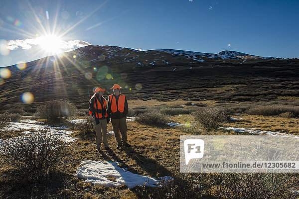 Großaufnahme eines Jägers und einer Jägerin in natürlicher Umgebung mit Bergen im Hintergrund