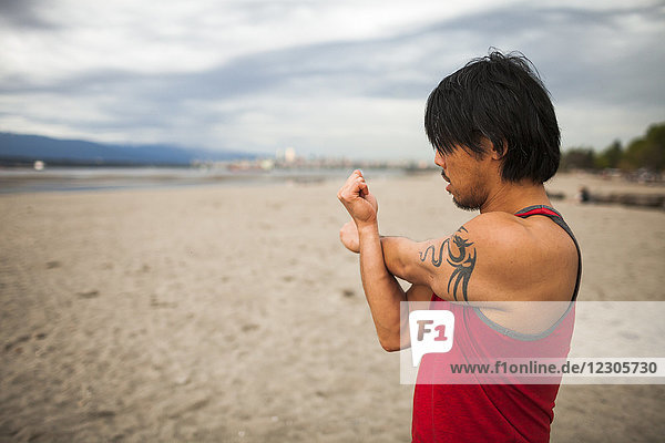 Man stretching before doing acroyoga at beach
