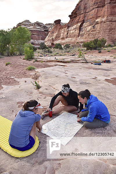Gruppe von drei Wanderinnen mit Blick auf die Karte im Canyonlands National Park  Moab  Utah  USA