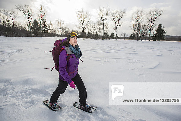 Frau mit Skibrille und Jacke beim Schneeschuhlaufen im Freien im Winter