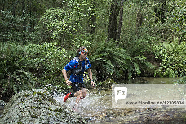 Young athlete running through pond in forest during trail run  Hidalgo  Mexico