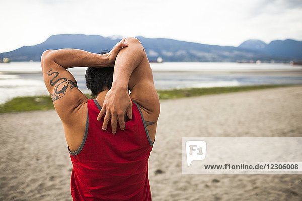 Man stretching before doing acroyoga at beach