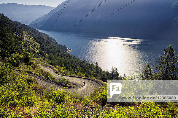 Landscape with motorcyclist going along winding High Line Road Anderson Lake D'Arcy BC Canada