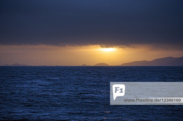 Meer bei bewölktem Sonnenuntergang mit Silhouetten von Küstenhügeln im Hintergrund  Porticcio  Korsika  Frankreich